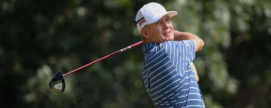 Professional Golfer Ken Duke In The Midst Of An Upper Swing At The Golf Course Wallpaper