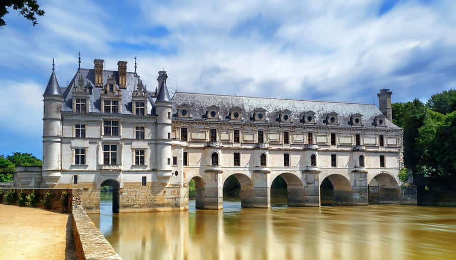 Scenic View Of Château De Chenonceau Over The Muddy River Wallpaper