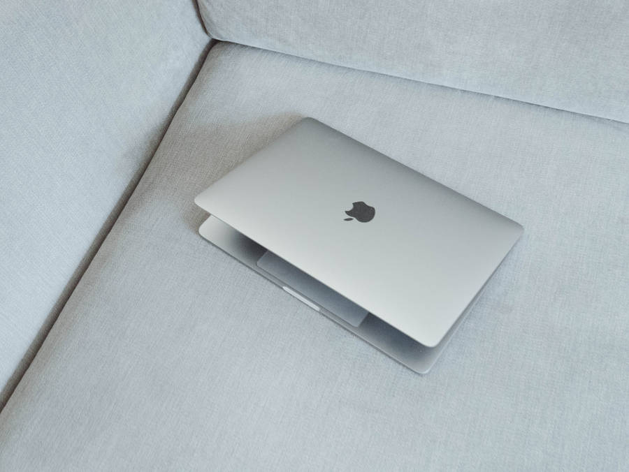 Silver Macbook On White Fabric Sofa Wallpaper