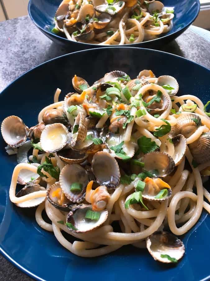 Sumptuous Spaghetti Alla Vongole Served On A Blue Plate Wallpaper