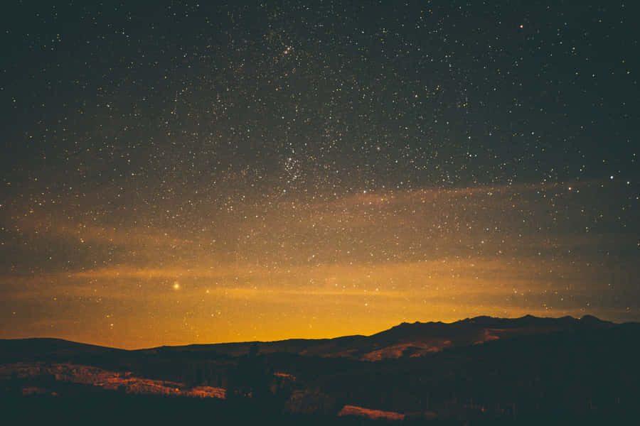 The Enchanting Night Sky Above The Hills Of A Village Wallpaper