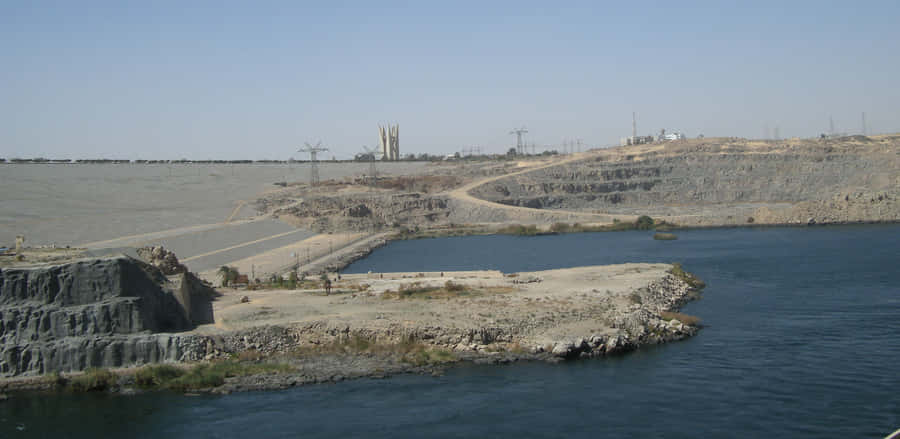 The Majestic Aswan High Dam Overlooking The Breathtaking Desert River Wallpaper