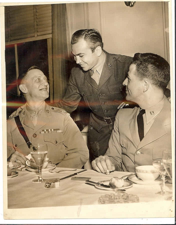 Three Men In Uniforms Sitting At A Table Wallpaper