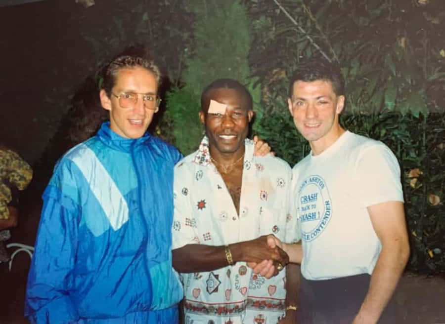 Three Men Shaking Hands Outdoors Wallpaper