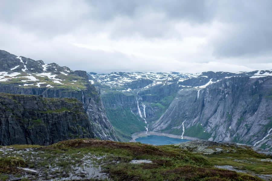 Trolltunga With Slight Snowy Peaks Wallpaper