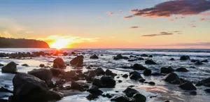 A Beach With Rocks And A Sunset Wallpaper