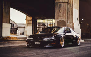 A Black Car Parked Under An Overpass Wallpaper