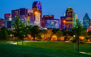 A City Skyline With A Park And Trees At Night Wallpaper