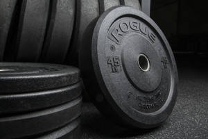 A Close-up Shot Of Rogue Barbell Plates Stacked Diligently On A Rack Wallpaper