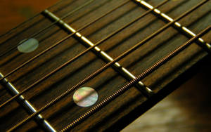 A Close Up View Of Fretboard Strings On A Guitar Wallpaper