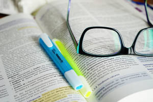 A Close-up View Of Reference Book, Highlighters, And Eyeglasses Wallpaper