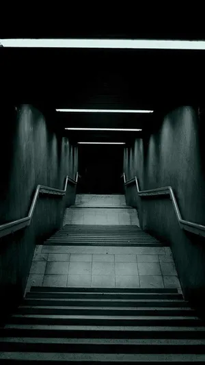 A Dark Hallway With Stairs Leading Down To A Dark Room Wallpaper