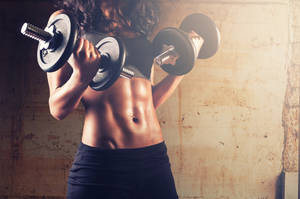 A Female Instructor Lifting And Challenging Her Fitness With Dumbbells Wallpaper