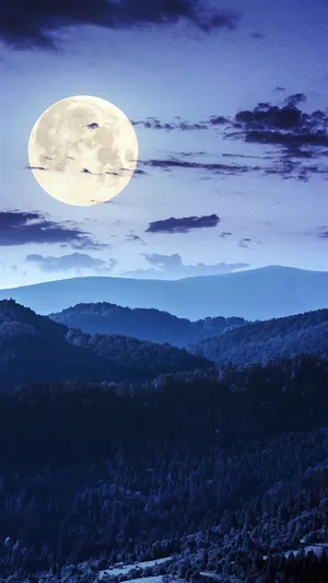 A Full Moon Rising Over A Mountain Wallpaper