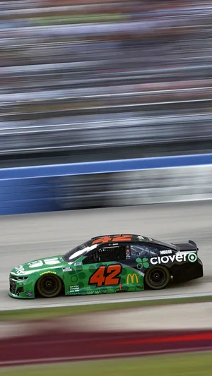 A Green Nascar Car Is Driving On A Track Wallpaper