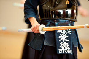 A Kendo Practitioner Holds A Bamboo Sword (shinai) Wallpaper