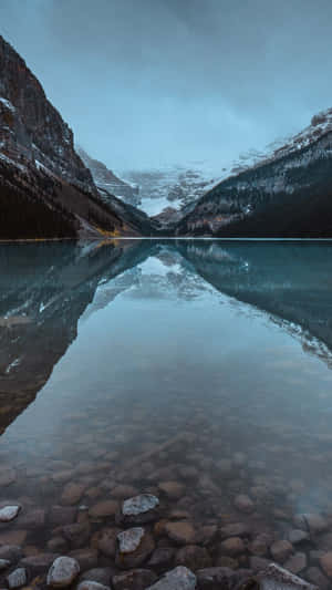 A Lake With Rocks And A Mountain In The Background Wallpaper