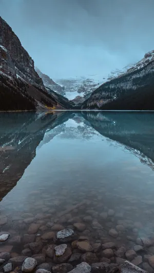 A Lake With Rocks And A Mountain In The Background Wallpaper