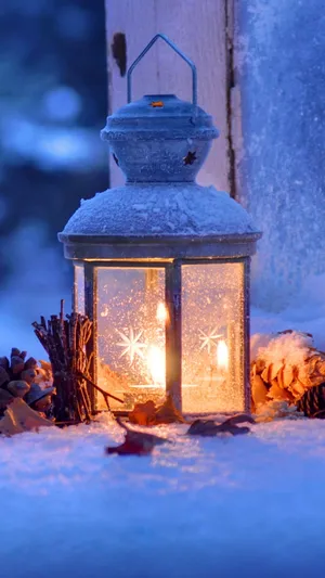 A Lantern Is Lit Up In The Snow Wallpaper