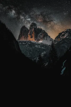 A Majestic View Of The Night Sky Over A Snow-capped Mountain Wallpaper