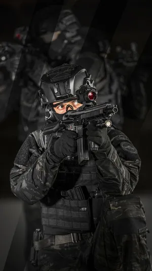 A Man In A Black Uniform Is Holding A Gun Wallpaper