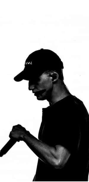 A Man In A Cap Holding A Microphone Wallpaper