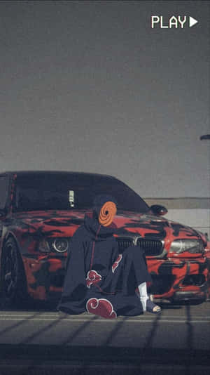 A Man Is Sitting On The Ground Next To A Red Car Wallpaper