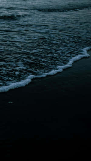 A Man Is Walking On The Beach At Dusk Wallpaper