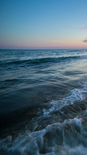 A Man Is Walking On The Beach At Dusk Wallpaper