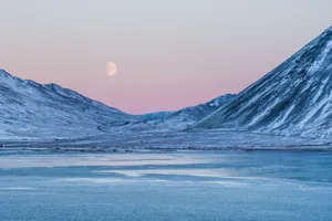 A Moon Rises Over A Mountain And Water Wallpaper