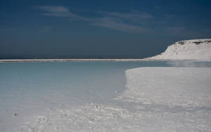 A Picturesque River Flowing Through Snow-covered Shores Wallpaper