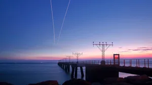 A Plane Flying Over A Pier At Sunset Wallpaper
