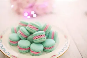A Plate Of Pink And Green Macarons On A Table Wallpaper