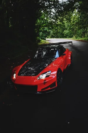 A Red Sports Car Is Parked In The Woods Wallpaper