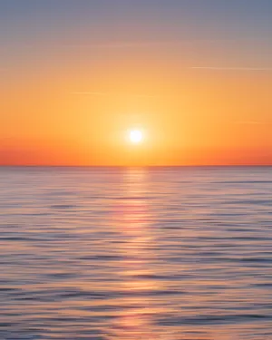 A Stunningly Beautiful Sunset Over The Calm And Inviting Ocean. Wallpaper