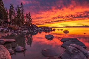 A Sunset Over A Lake With Rocks And Trees Wallpaper