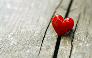 A Tiny Red Heart On A Wooden Floor Wallpaper