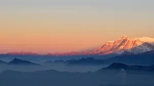 A View Of Snow-covered Mountain Ranges During A Breathtaking Sunset Wallpaper