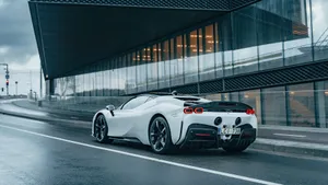 A White Sports Car Driving Down A Street Wallpaper