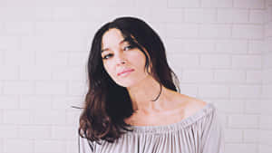 A Woman In A Gray Top Standing In A Bathroom Wallpaper