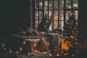A Woman Laying On A Bed With Christmas Lights Wallpaper