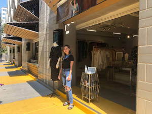 A Woman Standing In Front Of A Store With Clothes On Display Wallpaper