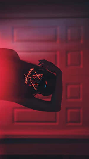 A Woman With A Red Neon Mask In Front Of A Door Wallpaper