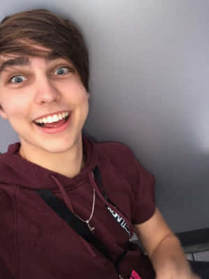 A Young Man Smiling While Sitting On A Toilet Wallpaper