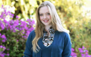 A Young Woman In A Blue Cardigan Standing In Front Of Flowers Wallpaper