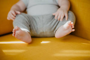 Adorable Newborn Baby Girl Seated In A Yellow Chair Wallpaper