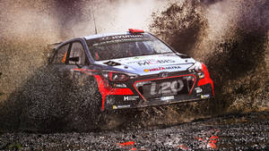 Adrenaline Packed Action - Racing Car Conquering A Muddy Road Wallpaper