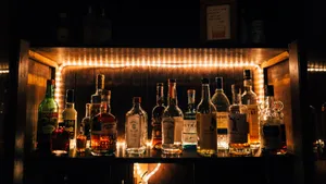 Alcohol Bottles On Shelf With Light Wallpaper