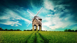 An Aerial View Of A Windmill Against A Grass-filled Landscape Wallpaper