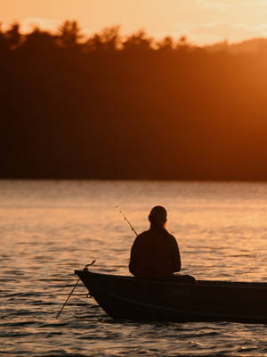 An Early Morning Angler Enjoying The Tranquility Of A Tranquil Fishing Boat. Wallpaper